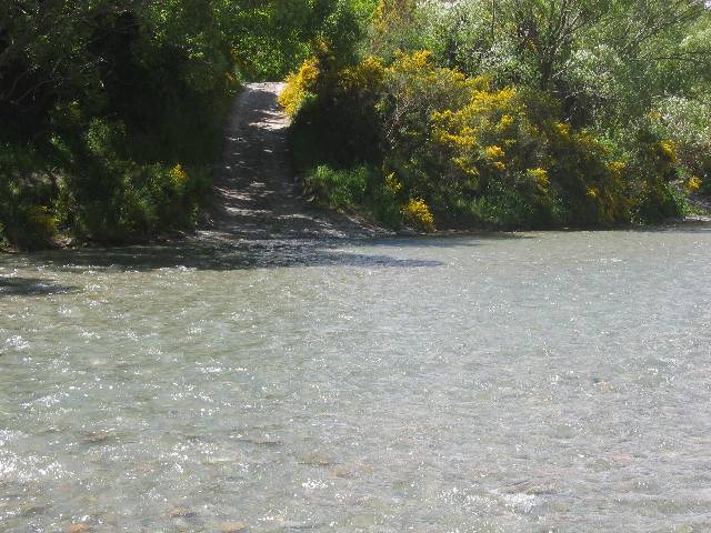 16-ArrowRiver Arrow River ... that path going up the hill is actually an old road that went between Arrowtown and a gold mining town a few miles upstream ... the road crossed the river multiple times, and our 4WD likewise forded multiple times ... the old abandoned gold mining town that's upstream had recently had one of the two remaining old wooden historic buildings burned down by an idiotic British tourist, who had seen the town on the map, decided to walk all the way to the town from Arrowtown to 