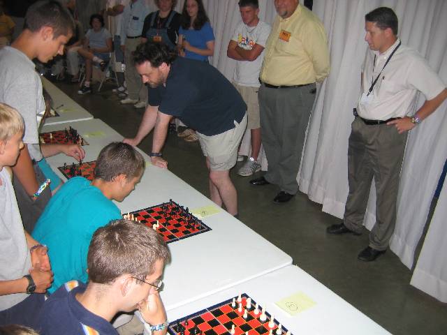 067-SarfatiChessChallenge Usually Dr Sarfati, who is a former New Zealand National Chess Champion and is a Grand Master, plays a dozen games simultaneously while blindfolded, but there wasn't anyone around that could confidently and accurately call out the grid-locations of the piece movement, so he played without the blindfold (but let each player choose their colour)